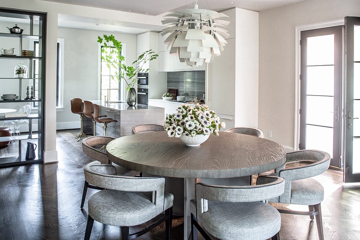 Dining room with a round oak table, gray chairs, and an artichoke pendant — Cleveland Park Residence by Christopher Patrick Interiors