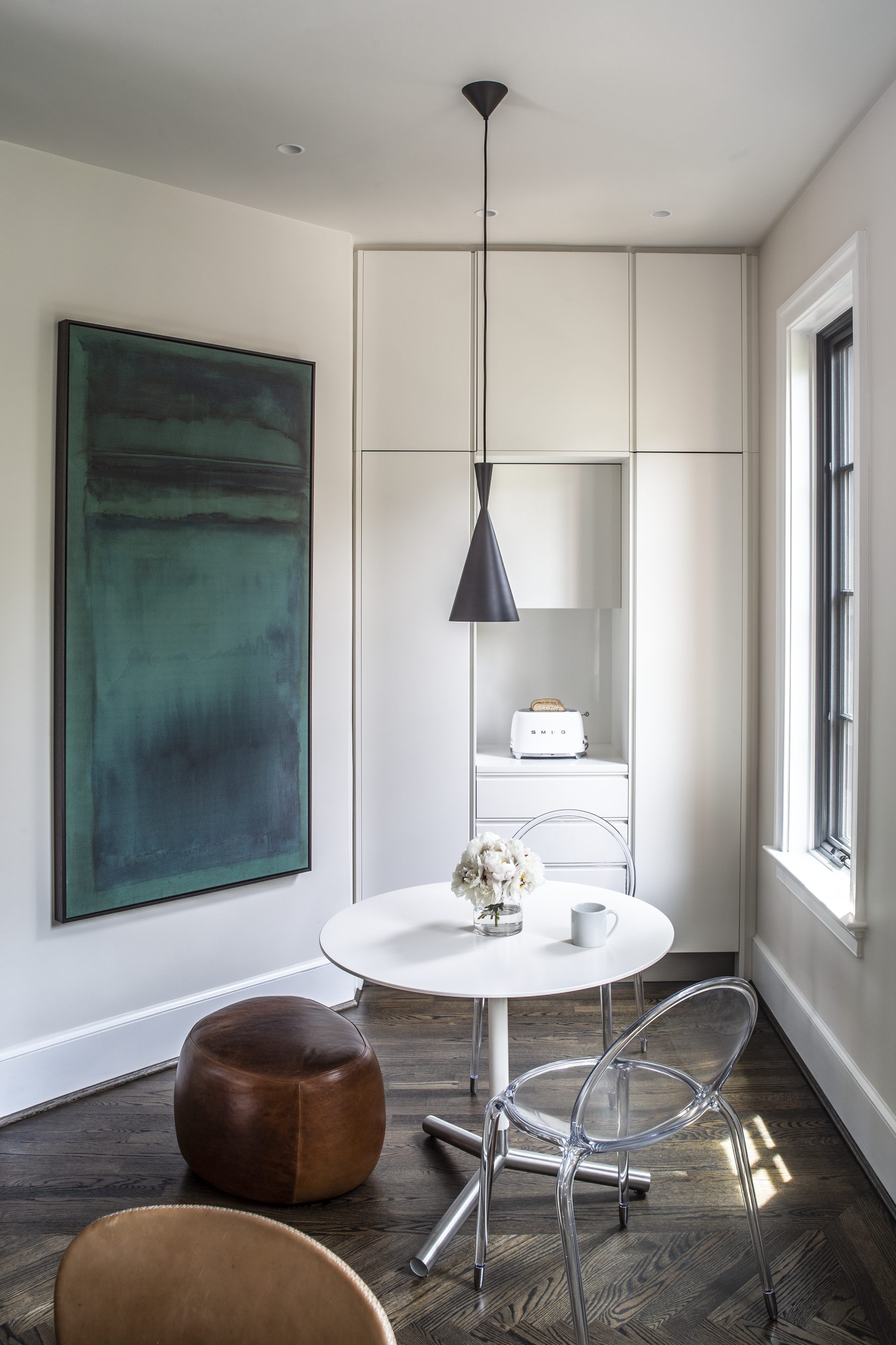 Breakfast nook with a tulip table, leather pouf, and a green abstract painting — Cleveland Park Residence by Christopher Patrick Interiors