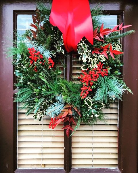 Evergreen holiday wreath with red berries and a red ribbon on a front door — holiday decorating by Christopher Patrick Interiors