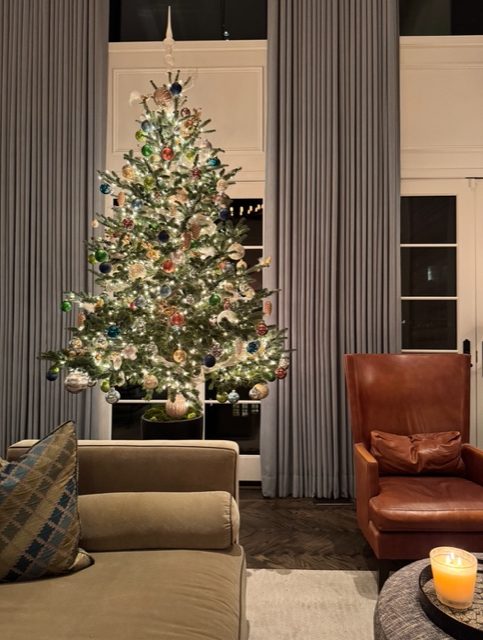 Decorated Christmas tree in a living room with a leather armchair — holiday decorating by Christopher Patrick Interiors